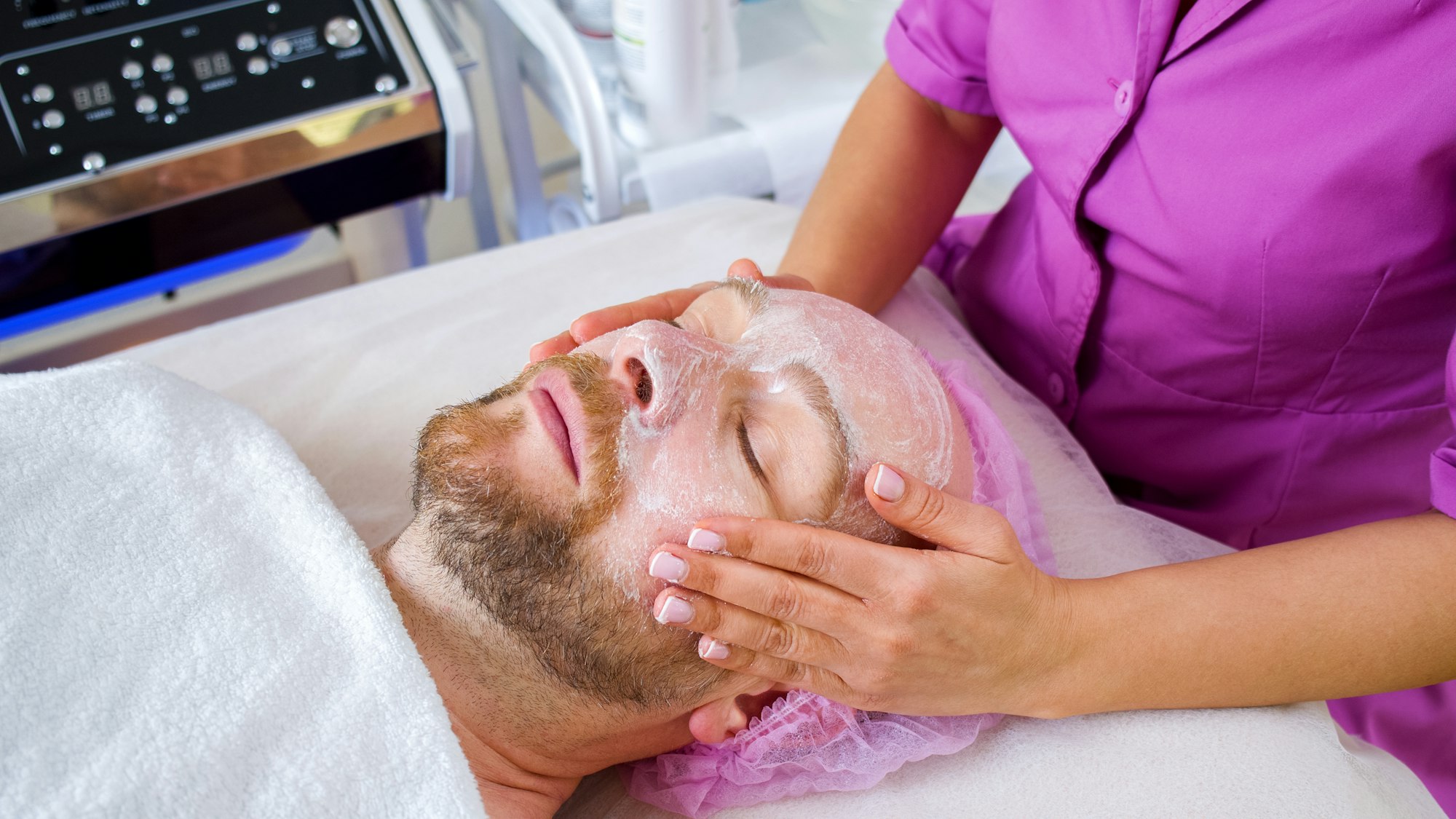 Cosmetologist makes a man a facial therapeutic.