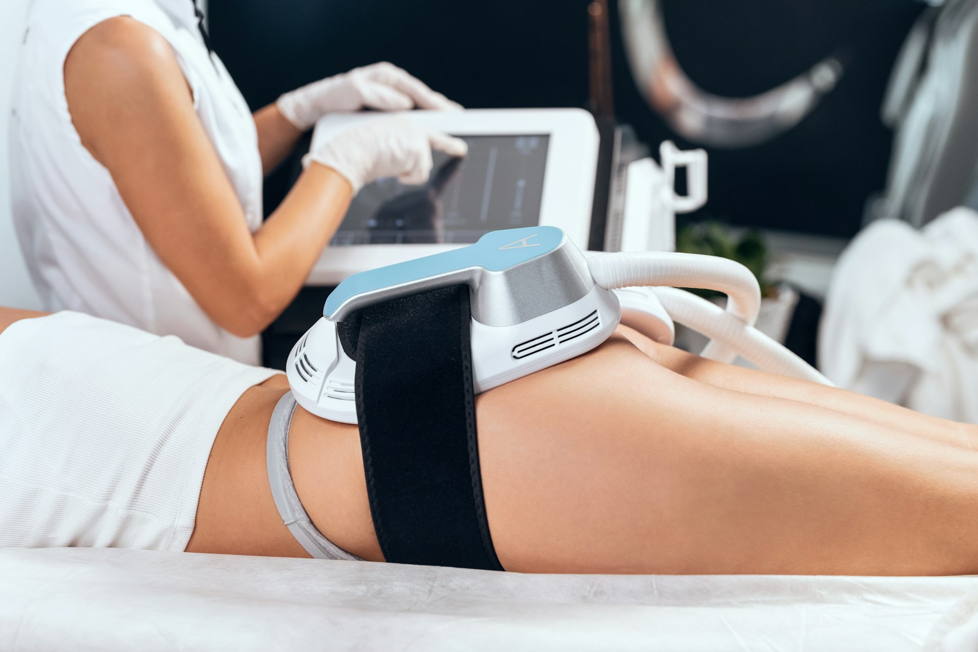 Woman lying receiving epilation laser treatment and anticellulite massage on buttock on the spa
