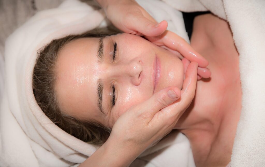 Professional esthetician performing a relaxing facial massage during a professional skincare treatment.