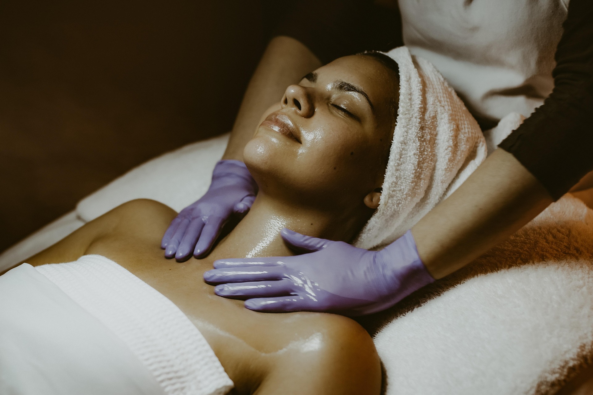 Professional spa therapist performing a relaxing neck and décolletage massage as part of a luxury facial skincare treatment.