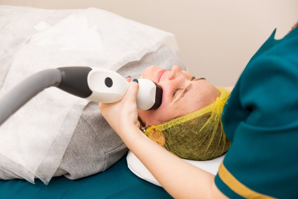 Patient receiving a non-invasive radiofrequency skin tightening treatment on the lower face and neck.