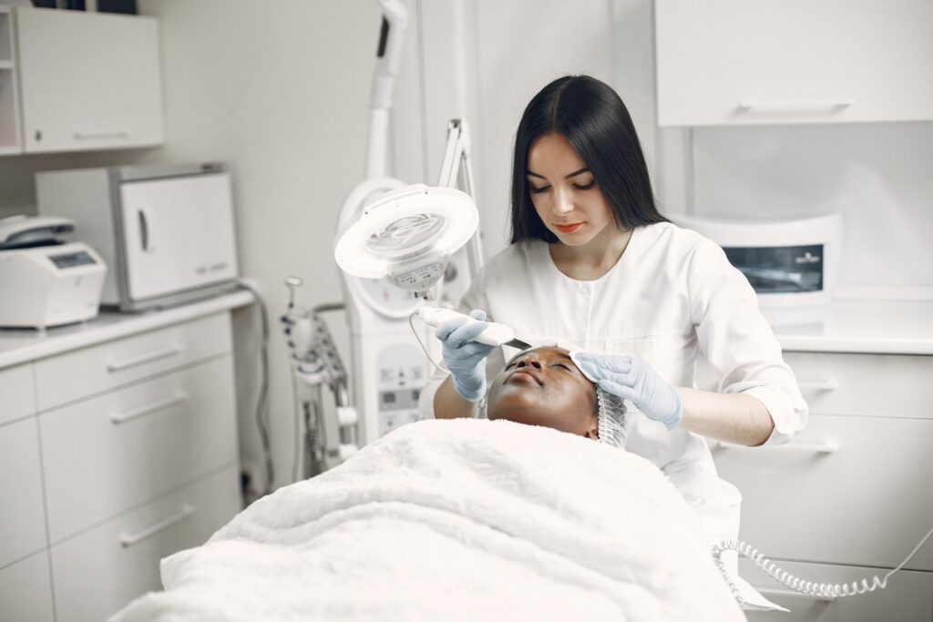 Licensed esthetician performing a professional facial treatment with advanced skincare equipment in a modern medical spa.