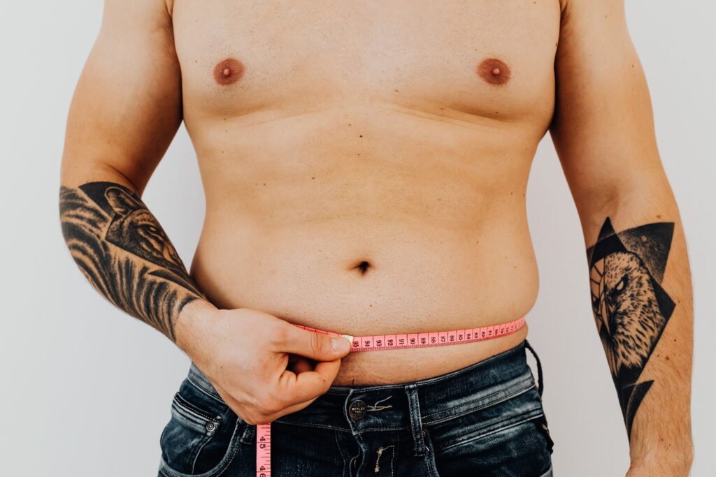 Man measuring his waist circumference to track body composition, weight loss, or body contouring progress.