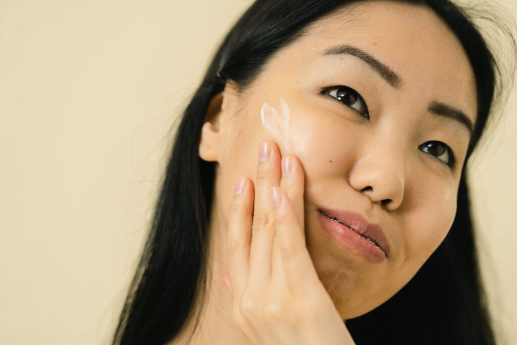 Woman applying facial moisturizer as part of a daily skincare routine for healthy skin.