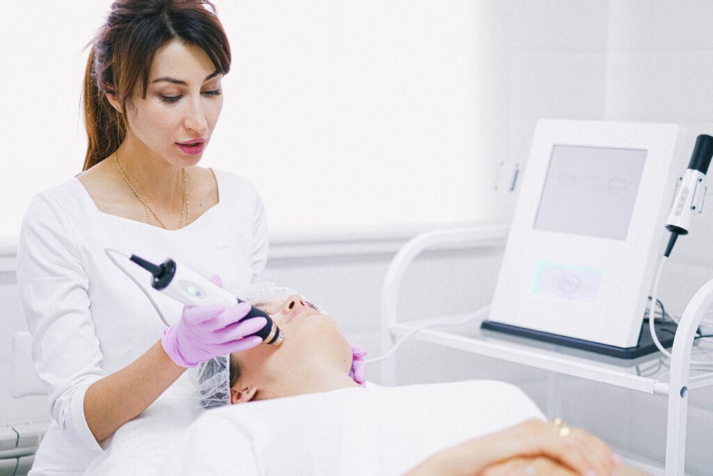 Licensed esthetician performing a non-invasive facial skin rejuvenation treatment using advanced skincare technology in a medical spa.