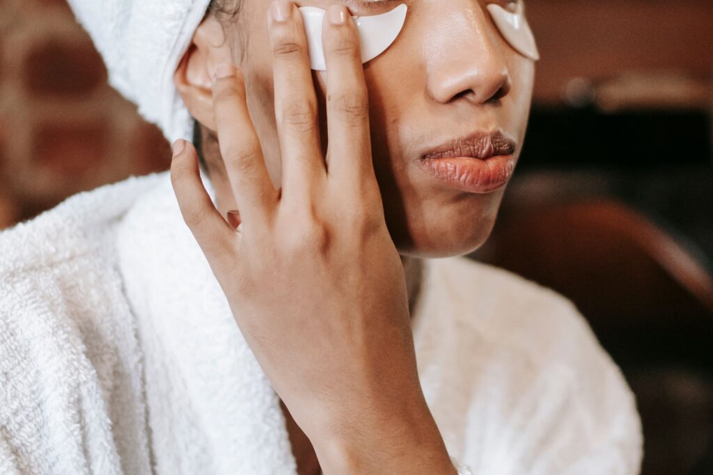 Person applying under-eye patches to reduce puffiness and hydrate the delicate eye area during a skincare routine.